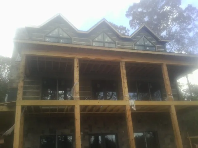 Dormers and porch framing on a large log home under construction — Roof Coating work by our crew in Montrose