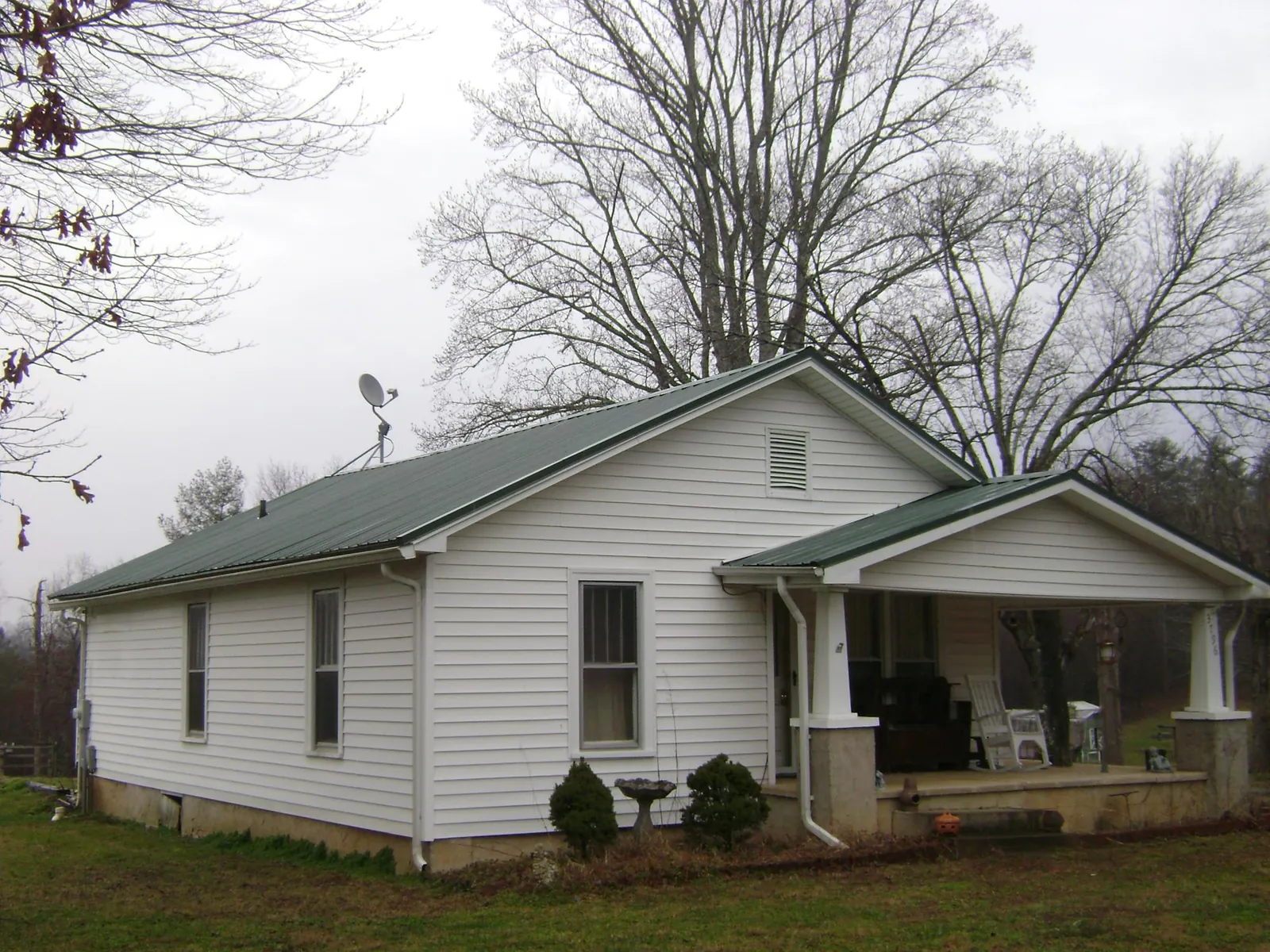 Green metal roof on a white bungalow with a side porch in Montrose